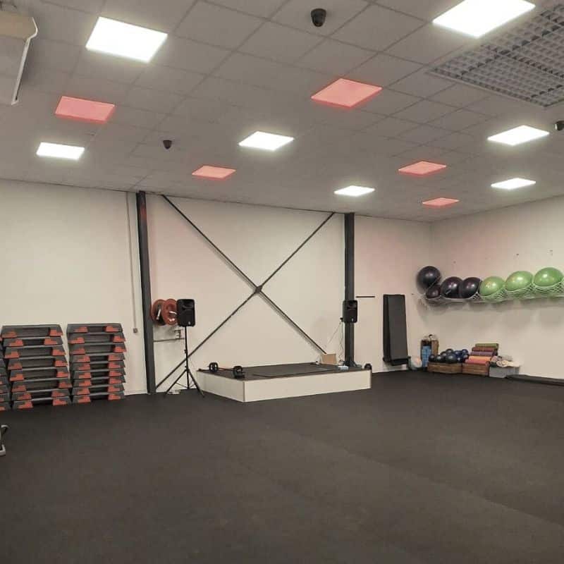 Salle de Fitness Équipée pour Cours Collectifs et Coaching Salle de sport équipée de steps, ballons de fitness et estrade centrale, idéale pour des cours collectifs.